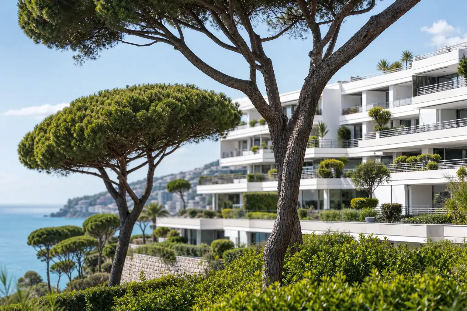Résidence balnéaire à terrasses étagées derrière des pins parasols